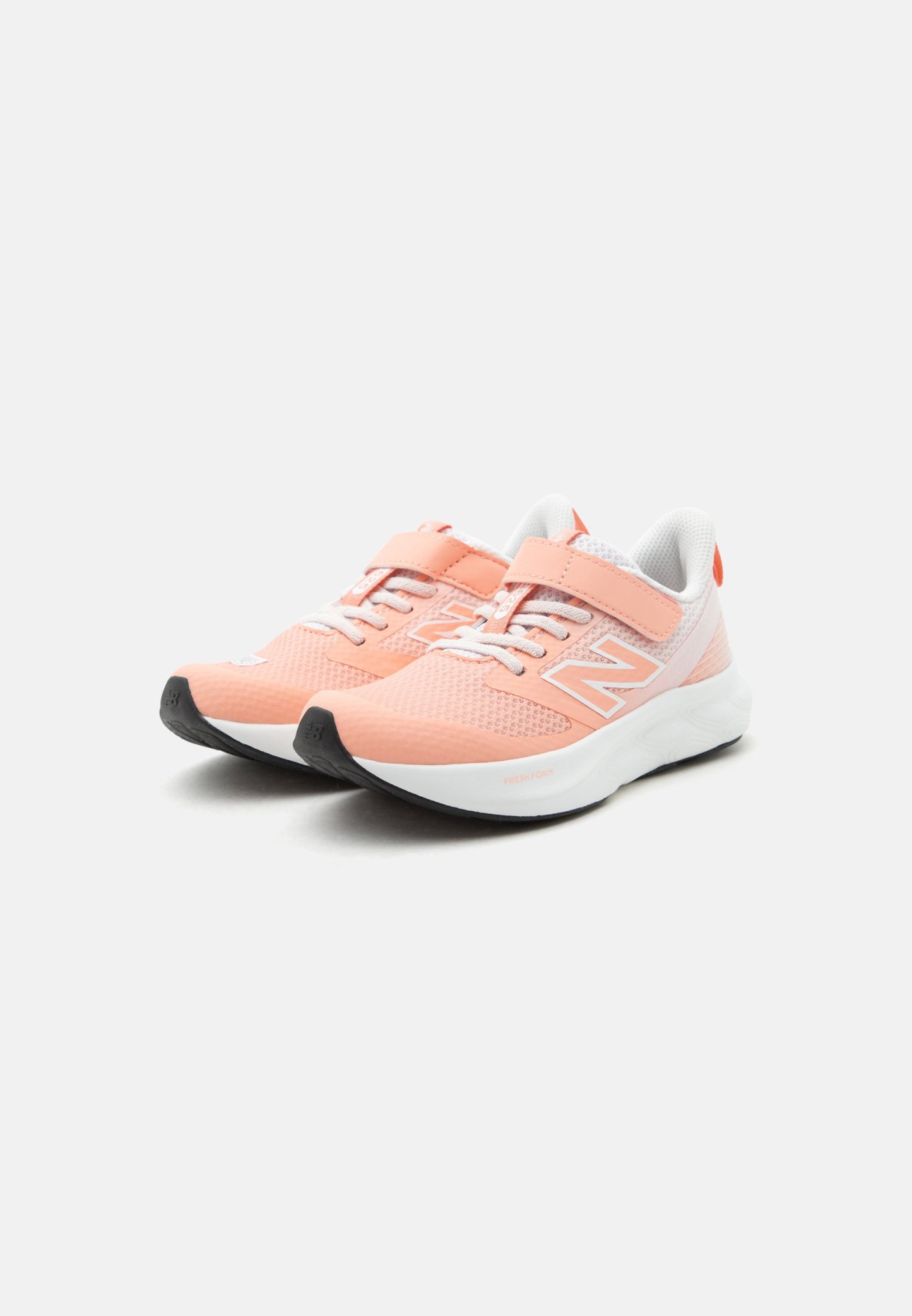 Par de zapatillas deportivas de coral claro con suelas blancas, parte superior de malla, cordones y una tira de velcro sobre fondo blanco.