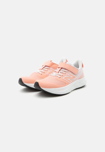 Par de zapatillas deportivas de coral claro con suelas blancas, parte superior de malla, cordones y una tira de velcro sobre fondo blanco.