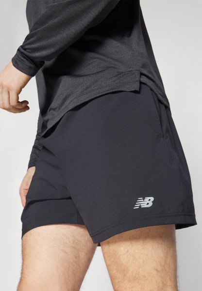 Pantalones cortos deportivos negros con una textura suave, que presentan un bolsillo lateral y un logotipo reflectante en la parte inferior izquierda.