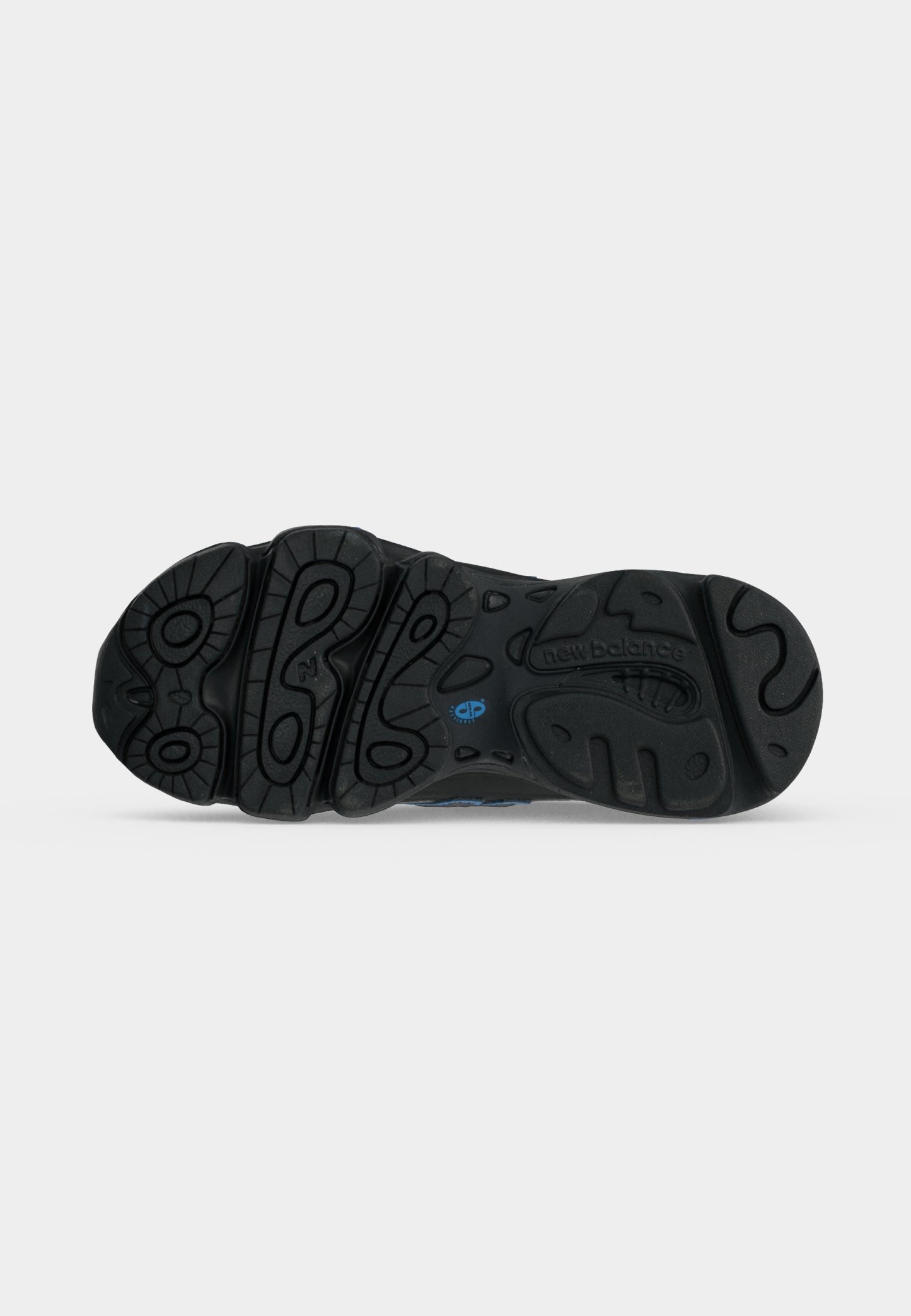 Suela negra de zapato New Balance con surcos profundos con patrones circulares y ondulados y un pequeño logo azul cerca del centro.