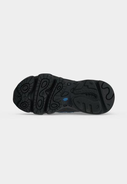 Suela negra de zapato New Balance con surcos profundos con patrones circulares y ondulados y un pequeño logo azul cerca del centro.