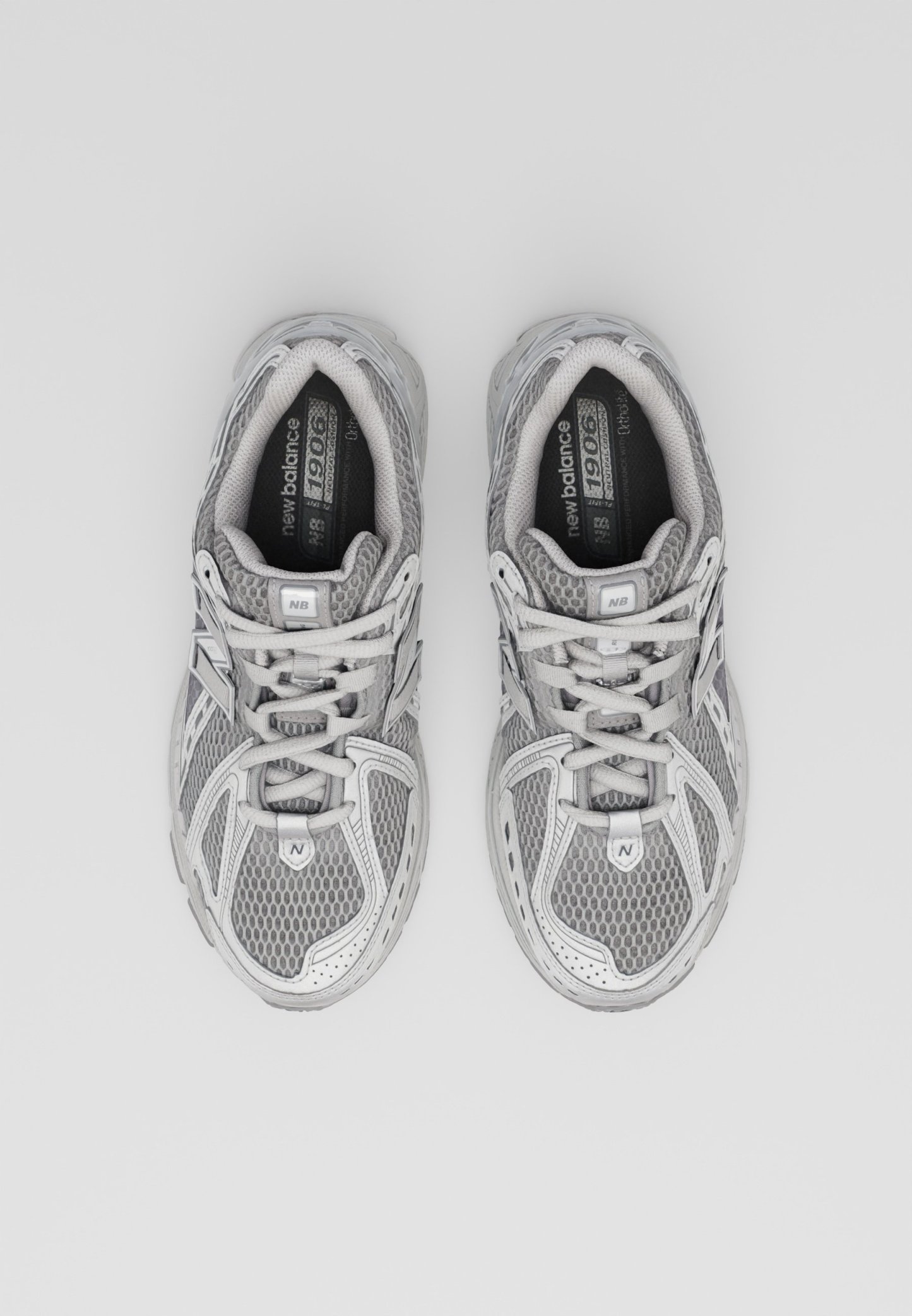 Zapatillas deportivas grises con parte superior de malla y sintético, cordones, cuello acolchado y suela de goma. Presenta detalles en gris claro y características de ventilación.