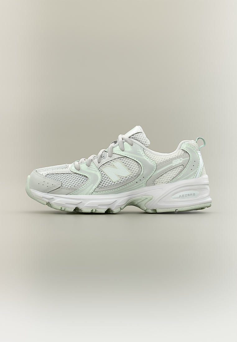 Zapatilla deportiva blanca y gris claro con paneles de malla, cordones, logo lateral de marca y suela acolchada sobre un fondo liso.