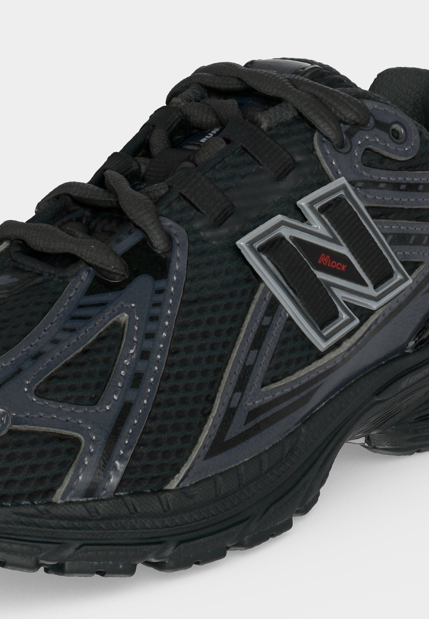 Zapatilla deportiva negra y gris con textura de malla, cierre con cordones y gran logo "N" con texto rojo "NLock" en el lateral.