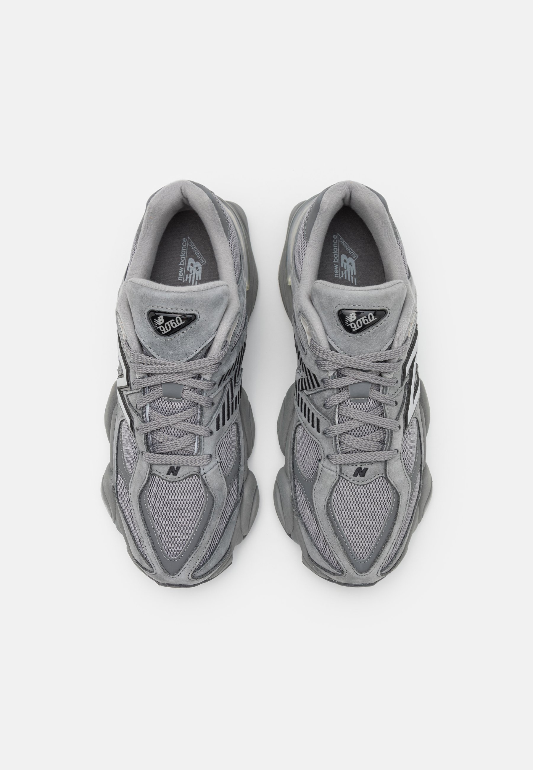 Par de zapatillas New Balance 9060 grises con detalles de malla y gamuza, diseño con cordones y suelas acolchadas, vistas desde arriba.