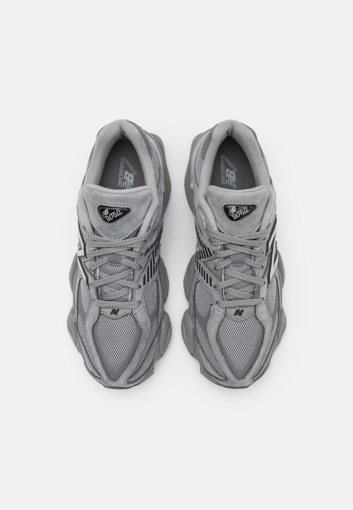 Par de zapatillas New Balance 9060 grises con detalles de malla y gamuza, diseño con cordones y suelas acolchadas, vistas desde arriba.