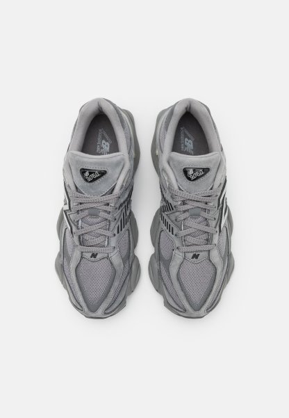 Par de zapatillas New Balance 9060 grises con detalles de malla y gamuza, diseño con cordones y suelas acolchadas, vistas desde arriba.