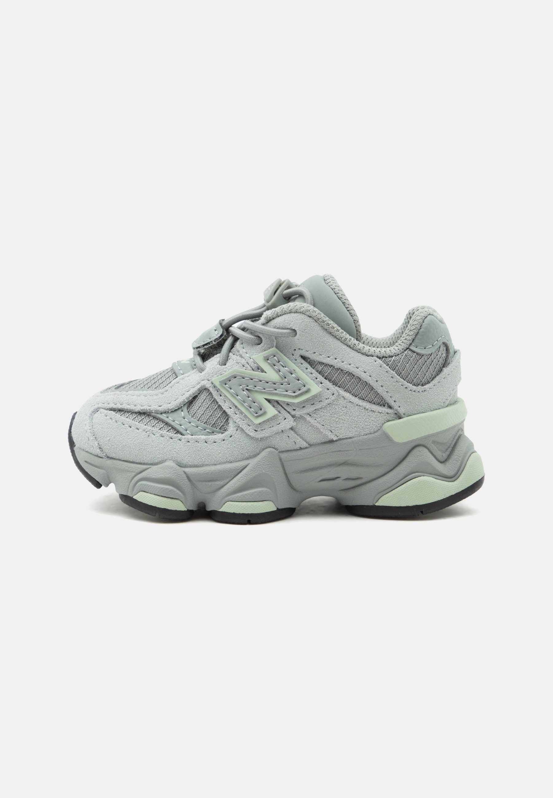 Zapatilla deportiva de color gris claro y verde menta con paneles de malla y ante, suela gruesa y detalle del logo en el lateral, vista desde el lado izquierdo.
