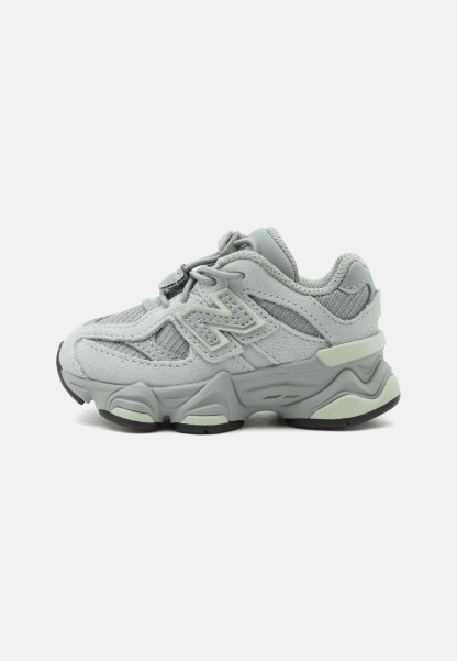 Zapatilla deportiva de color gris claro y verde menta con paneles de malla y ante, suela gruesa y detalle del logo en el lateral, vista desde el lado izquierdo.