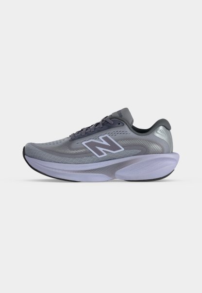 Zapatilla de running New Balance en gris y lavanda con parte superior de malla, suela acolchada y gran logotipo "N" en el lateral, mostrada de perfil sobre fondo blanco.