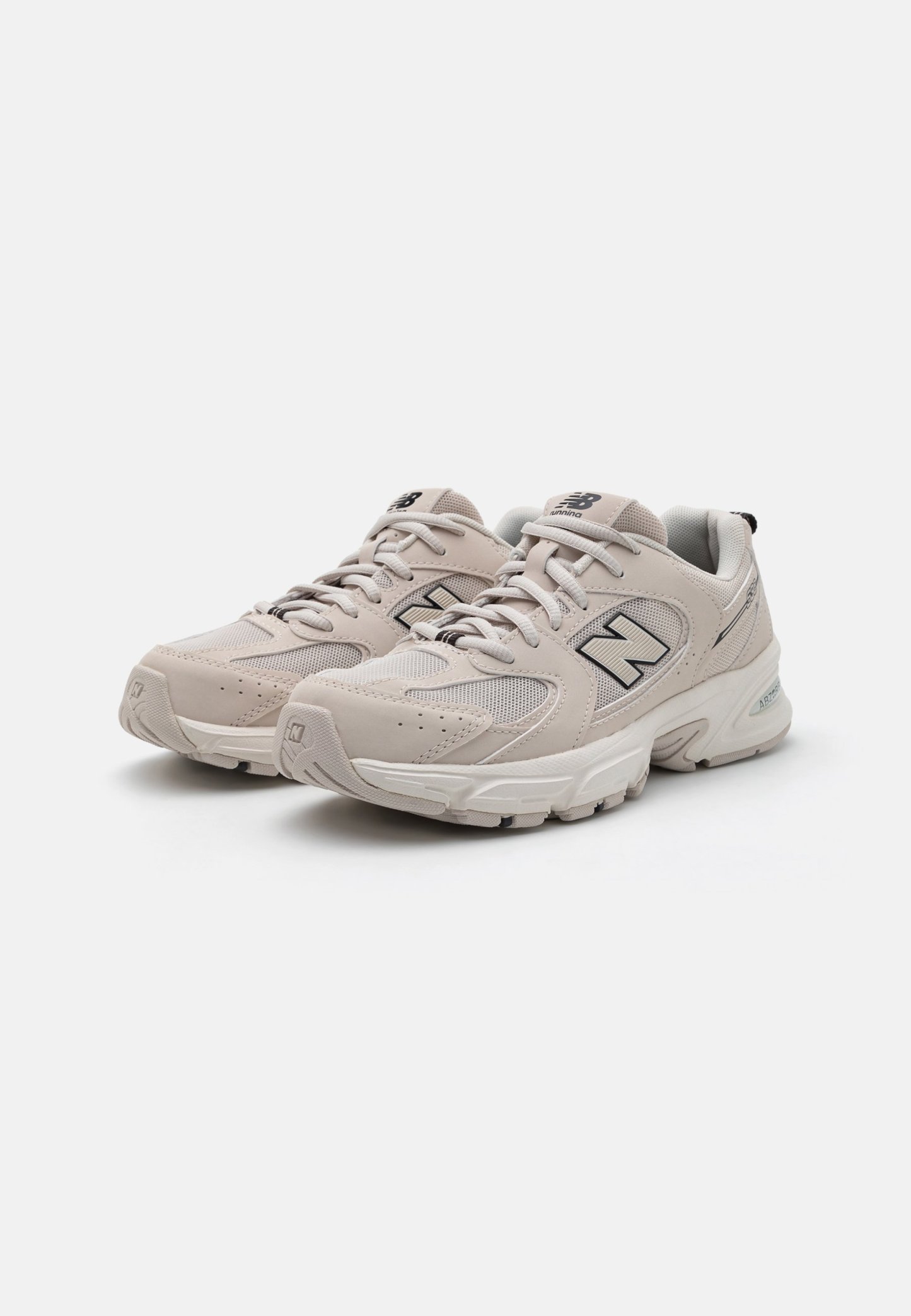 Zapatillas de correr color beige claro con superposición de malla y cuero, punta redondeada, parte frontal con cordones y suela acolchada. Presenta el logo 'N' y acentos texturizados.
