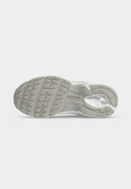 Suela de una zapatilla New Balance en gris claro con patrones de textura en la banda de rodadura y logotipo de la marca visible en el centro.
