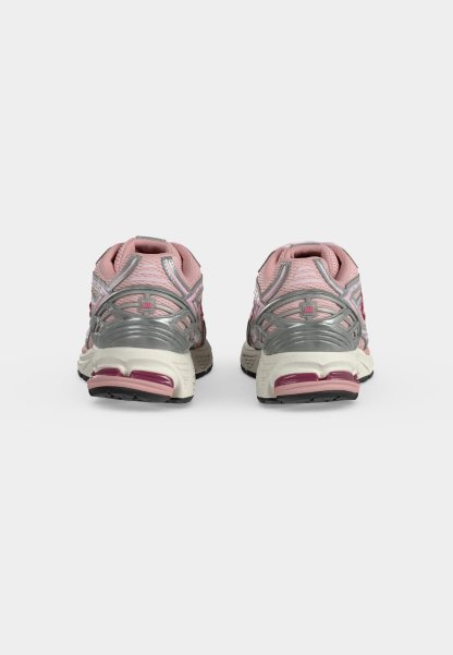 Par de zapatillas deportivas rosas y plateadas vistas desde atrás sobre un fondo liso gris claro.