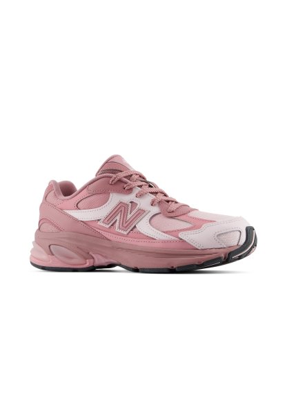 Zapatilla de running New Balance rosa y blanca con suela texturizada y cordones, mostrada de lado sobre un fondo blanco.