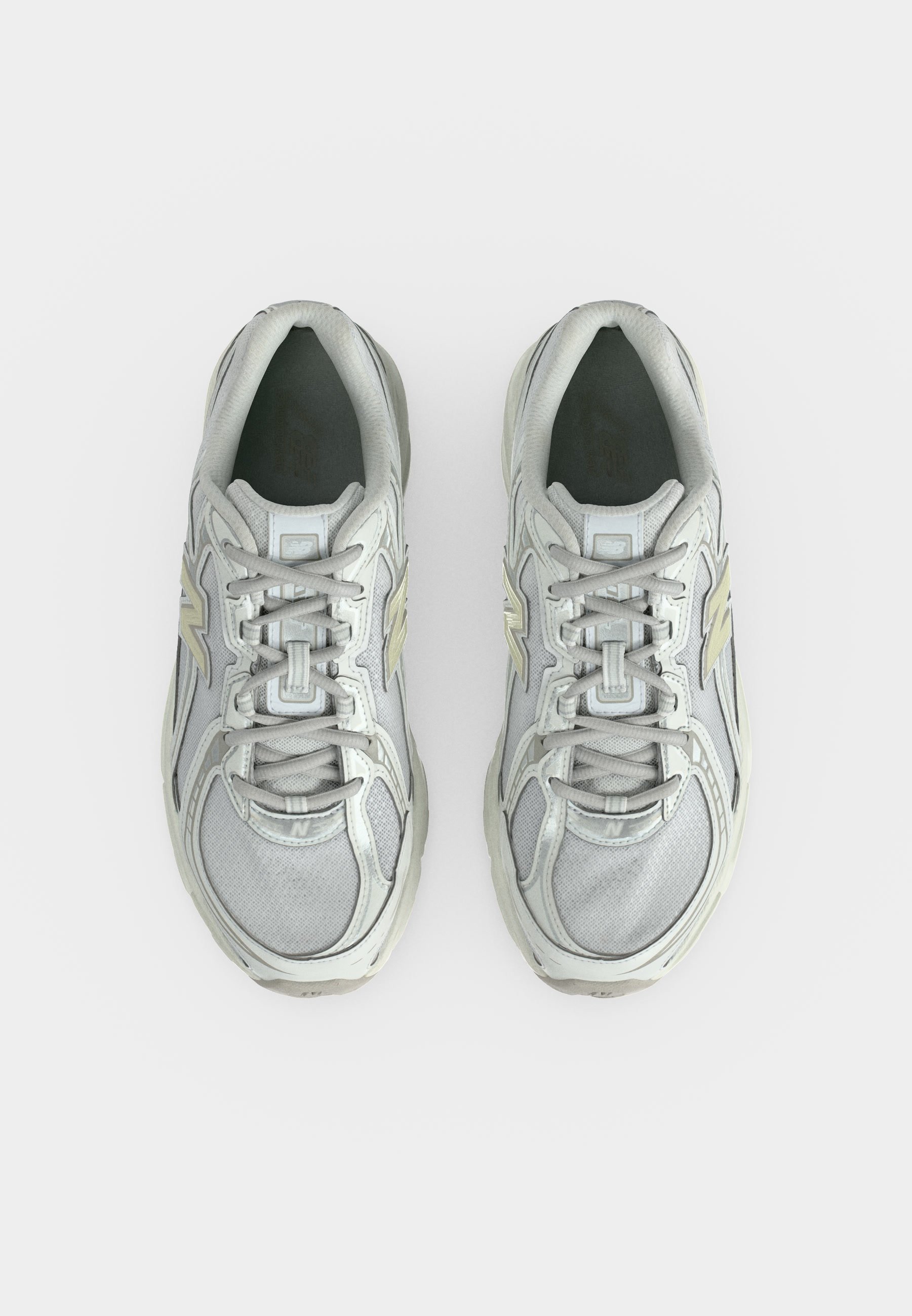 Par de zapatillas deportivas de color gris claro con detalles en blanco y beige, vistas desde arriba sobre un fondo blanco.