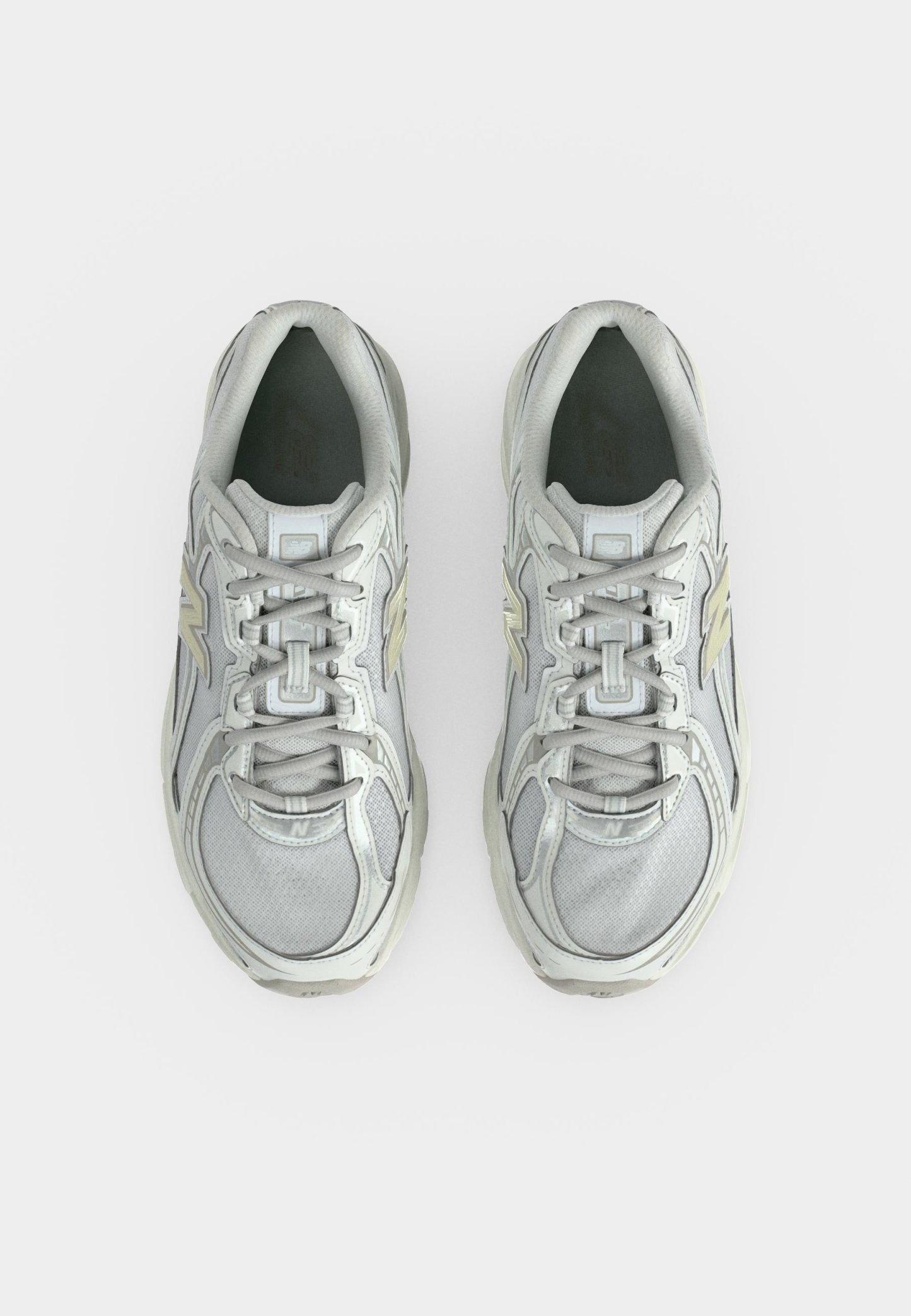 Par de zapatillas deportivas de color gris claro con detalles en blanco y beige, vistas desde arriba sobre un fondo blanco.