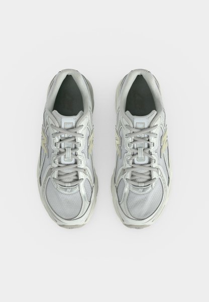 Par de zapatillas deportivas de color gris claro con detalles en blanco y beige, vistas desde arriba sobre un fondo blanco.