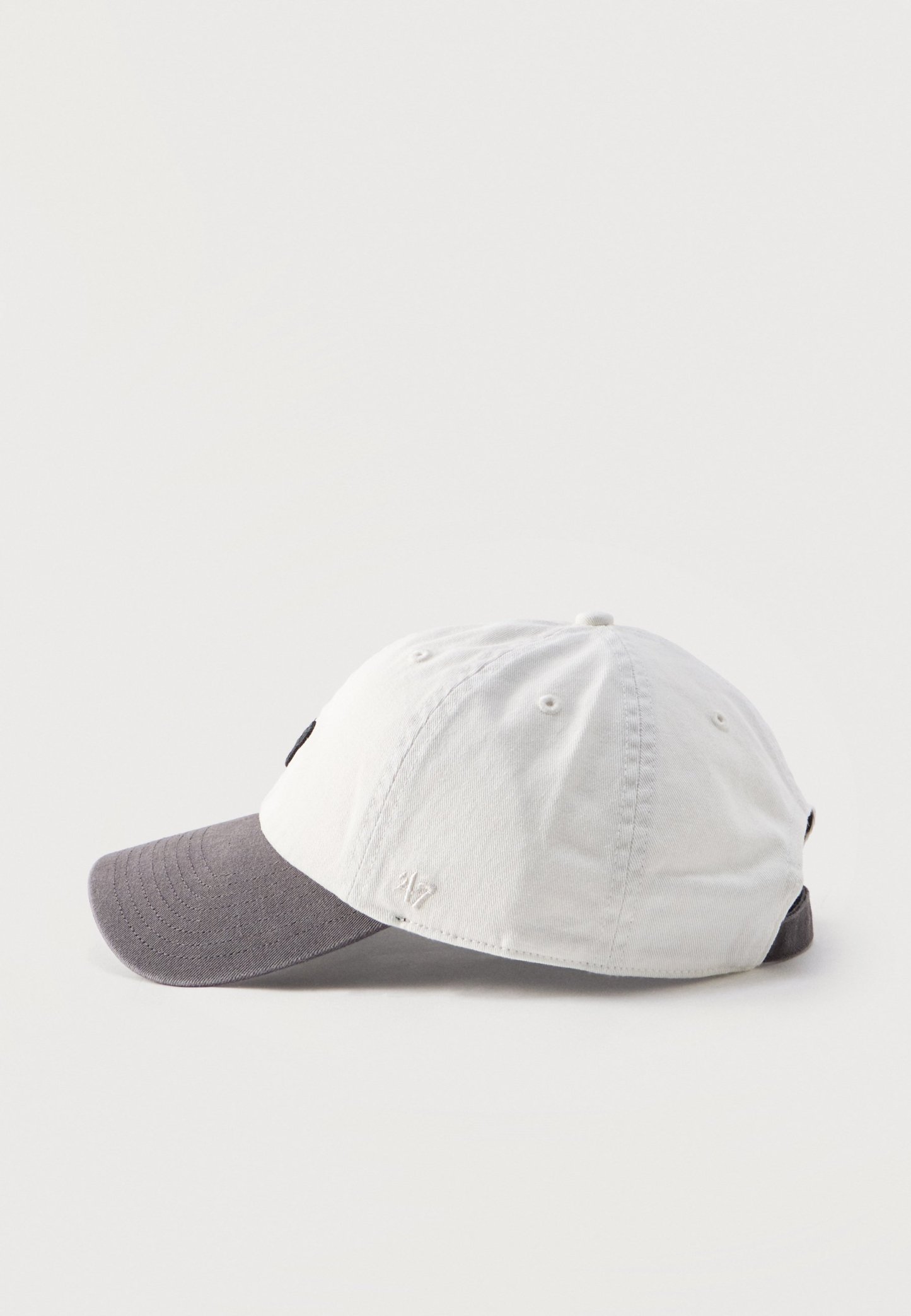 Gorra de béisbol con corona blanca y visera curva gris, mostrada de lado sobre un fondo claro.