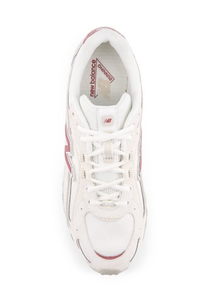 Zapatilla blanca para correr con materiales de malla y ante; cuenta con un logo "N" rojo, cordones y un cuello acolchado. Suela texturizada para mejor agarre.