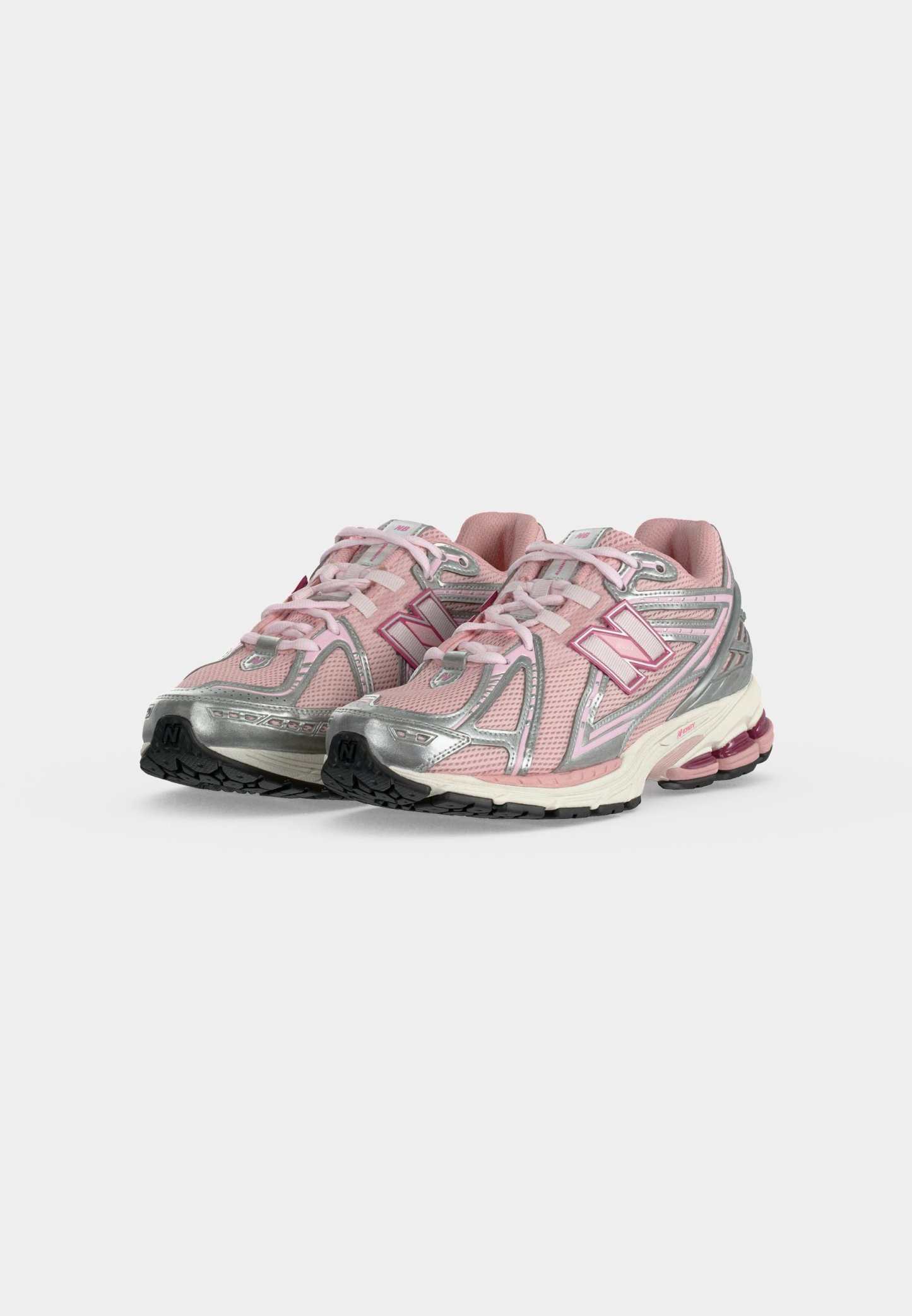 Par de zapatillas deportivas rosas y plateadas con cordones, suelas texturizadas y talones acolchados sobre un fondo claro y liso.