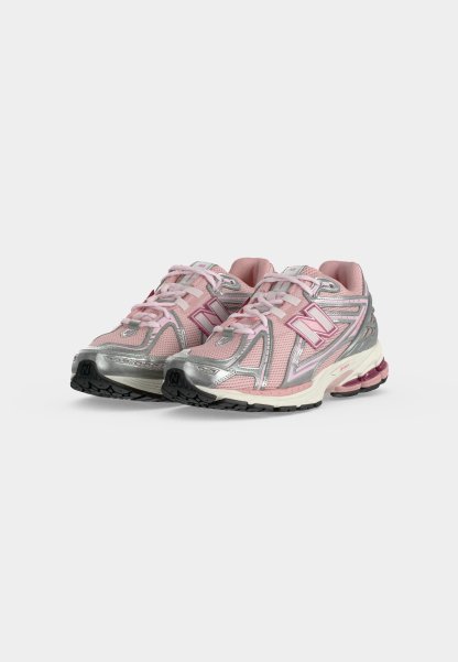 Par de zapatillas deportivas rosas y plateadas con cordones, suelas texturizadas y talones acolchados sobre un fondo claro y liso.