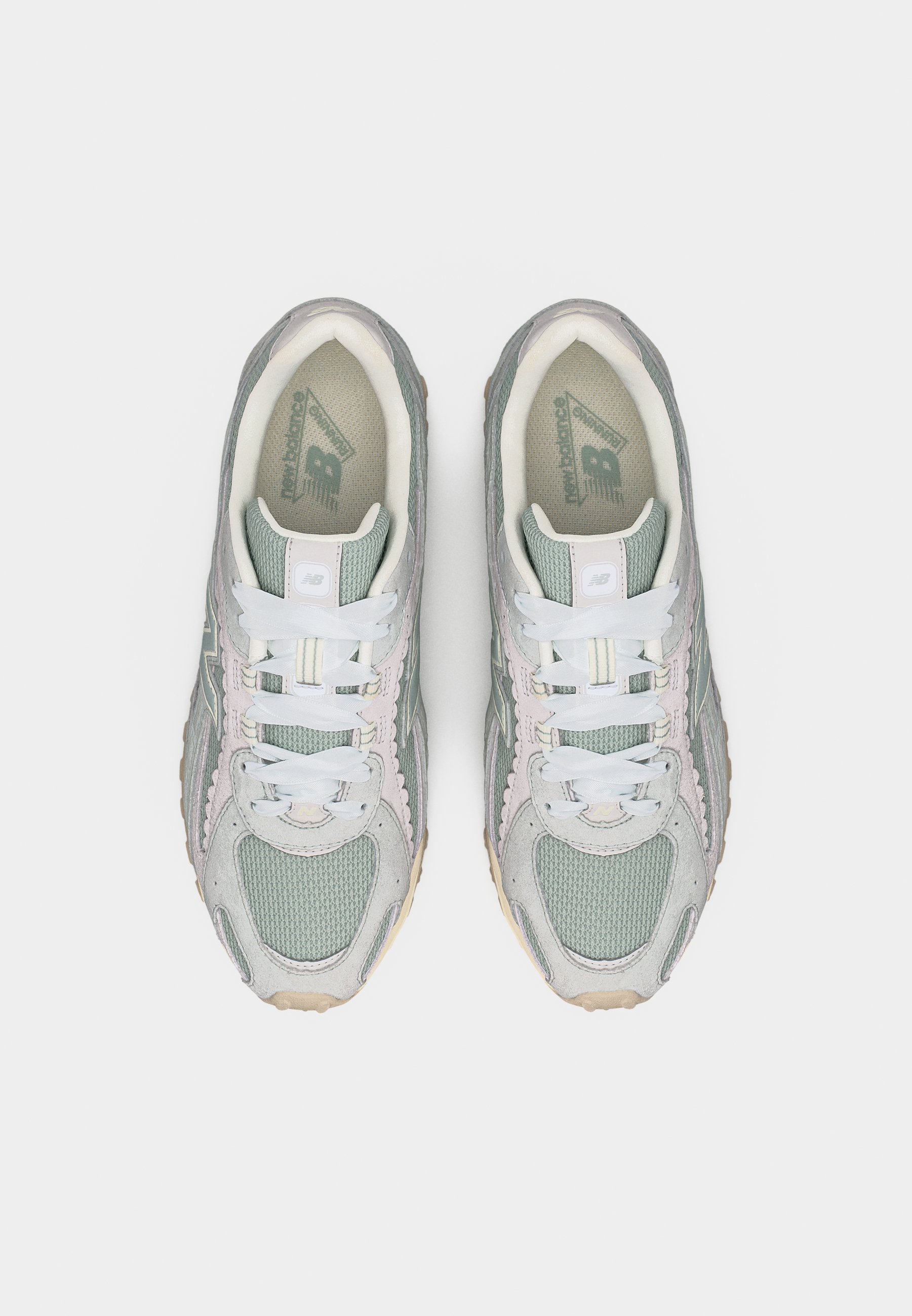 Par de zapatillas New Balance en tonos gris y verde pastel con cordones blancos, vistas desde arriba sobre un fondo liso.