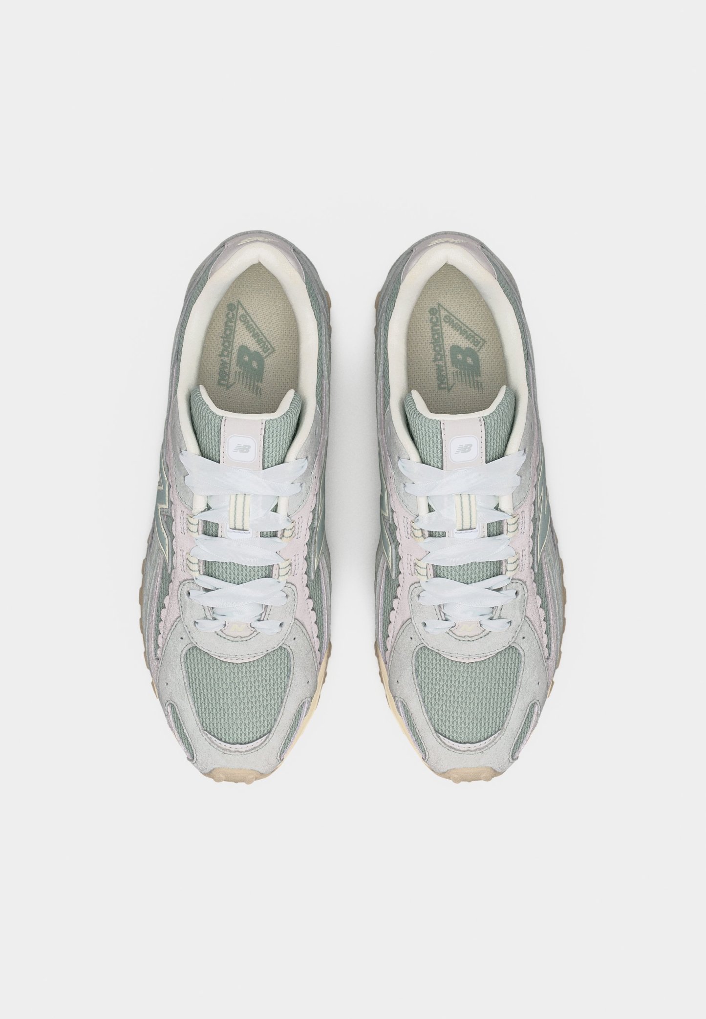 Par de zapatillas New Balance en tonos gris y verde pastel con cordones blancos, vistas desde arriba sobre un fondo liso.