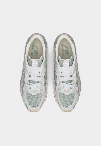 Par de zapatillas New Balance en tonos gris y verde pastel con cordones blancos, vistas desde arriba sobre un fondo liso.