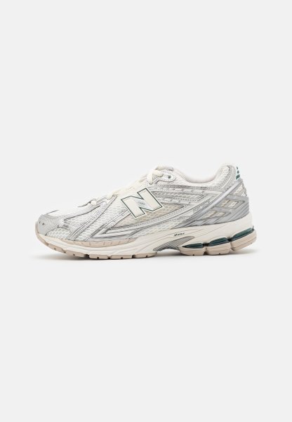 La zapatilla de correr presenta una parte superior de malla plateada y blanca con un acento verde. La suela es gruesa y texturizada, diseñada para ofrecer amortiguación y soporte.