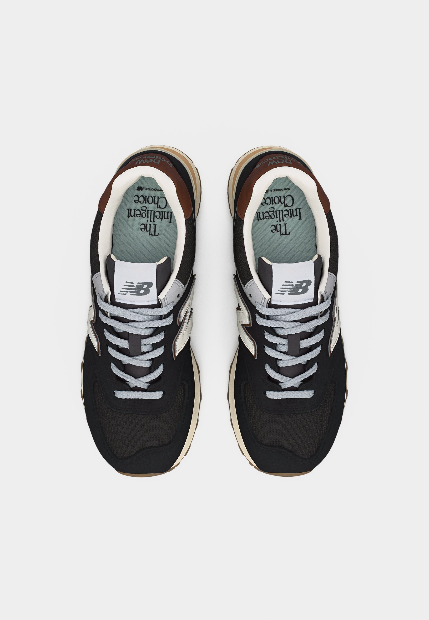 Par de zapatillas New Balance en blanco y negro con cordones grises, suelas beige y plantilla azul verdosa con la etiqueta "La Elección Inteligente".