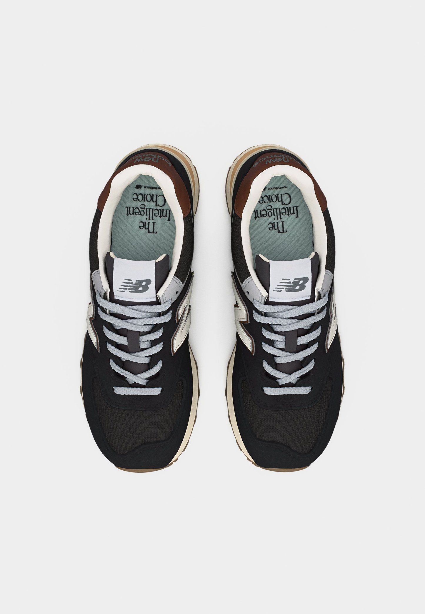 Par de zapatillas New Balance en blanco y negro con cordones grises, suelas beige y plantilla azul verdosa con la etiqueta "La Elección Inteligente".