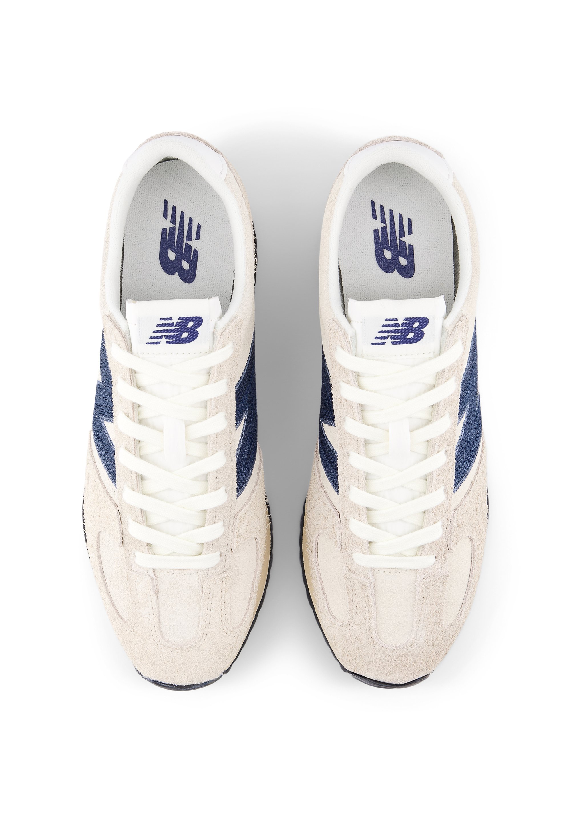 Zapatillas con parte superior de ante color beige, detalles laterales en azul marino y cordones blancos. Presentan una lengüeta acolchada y un logo en la plantilla. Diseño de puntera redonda.