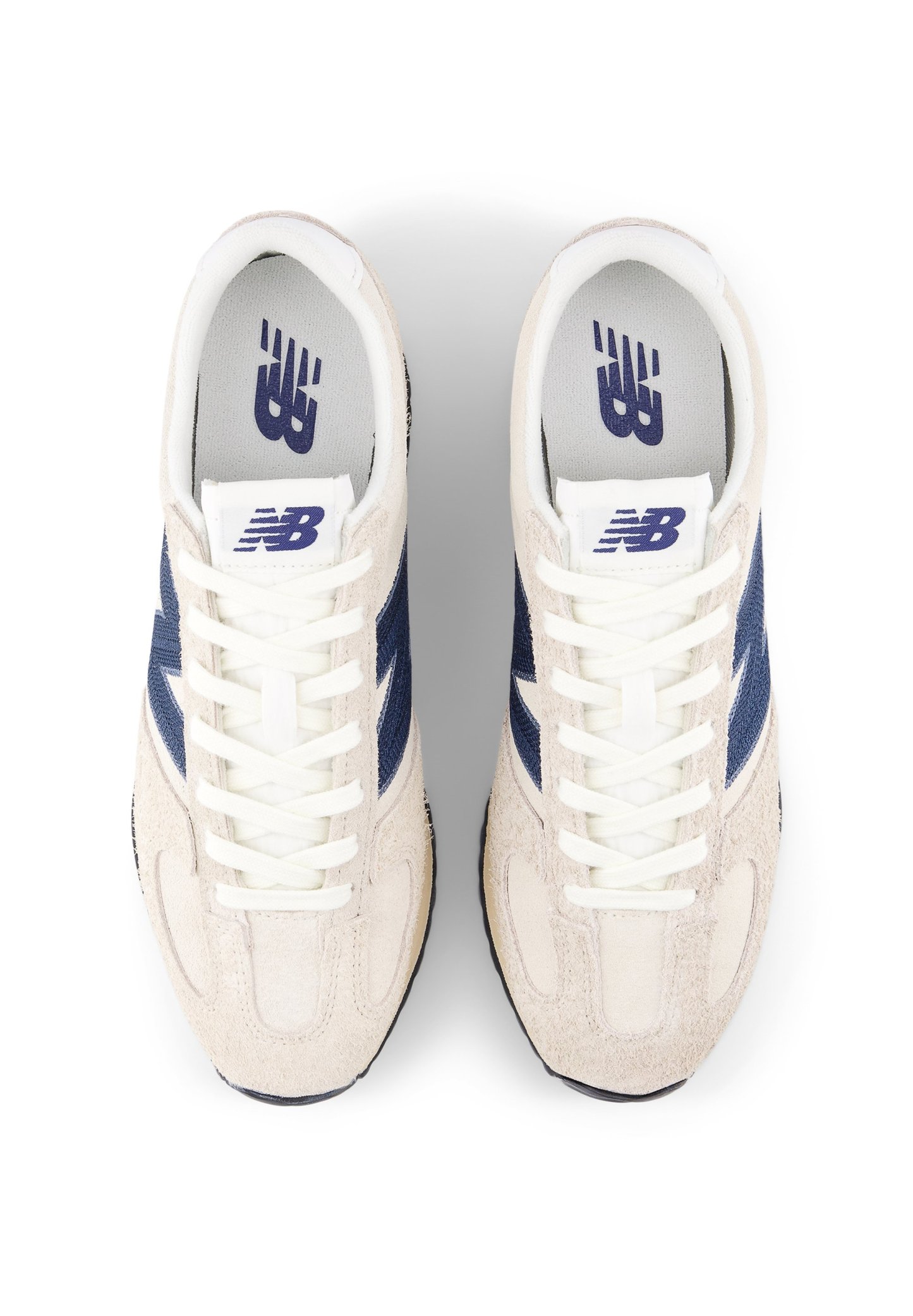 Zapatillas con parte superior de ante color beige, detalles laterales en azul marino y cordones blancos. Presentan una lengüeta acolchada y un logo en la plantilla. Diseño de puntera redonda.