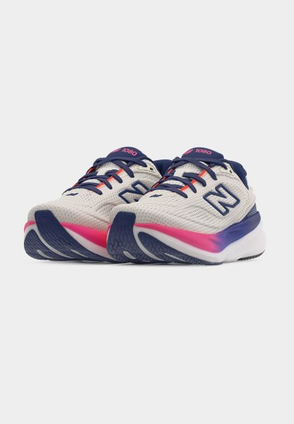 Par de zapatillas deportivas blancas con cordones azul marino, detalles en la suela en rosa y morado, y "1080" en la lengüeta azul marino.