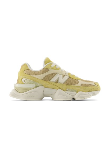 Zapatilla New Balance de color amarillo claro y beige con paneles de malla, suela gruesa y cordones blancos mostrada de perfil.