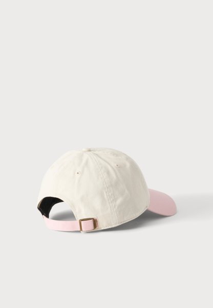 Gorra de béisbol beige claro con una correa ajustable rosa y una visera curva rosa sobre un fondo claro liso.
