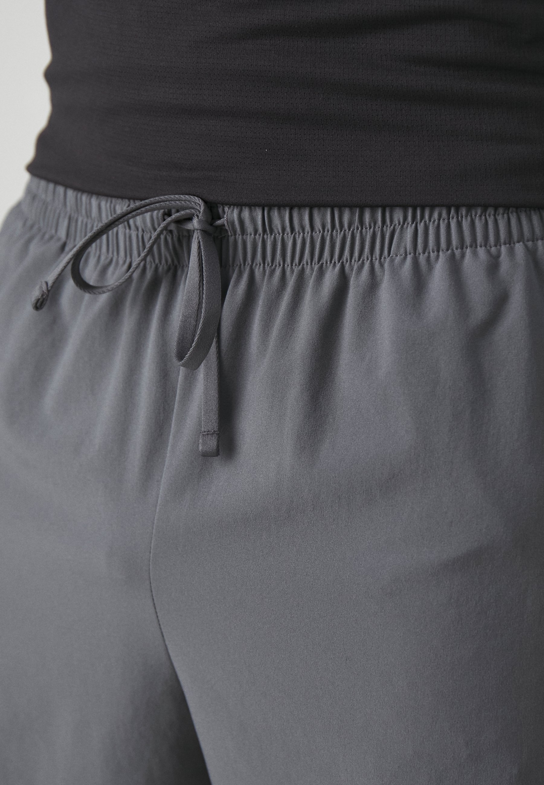 Pantalones cortos deportivos grises con cintura ajustable, fabricados en un tejido suave y ligero, y con un corte holgado, aptos para ropa de actividad.