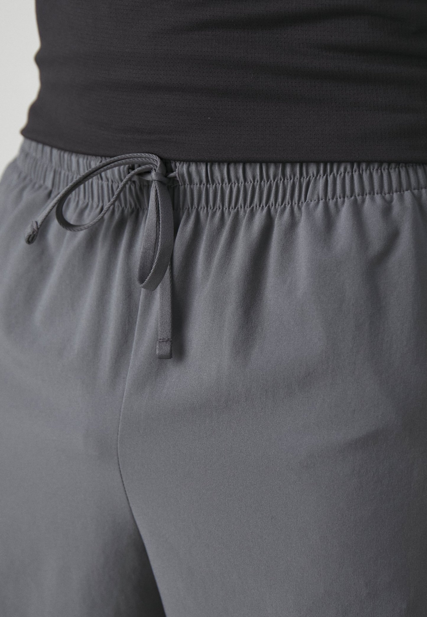 Pantalones cortos deportivos grises con cintura ajustable, fabricados en un tejido suave y ligero, y con un corte holgado, aptos para ropa de actividad.