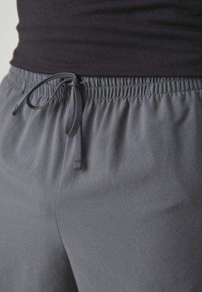 Pantalones cortos deportivos grises con cintura ajustable, fabricados en un tejido suave y ligero, y con un corte holgado, aptos para ropa de actividad.