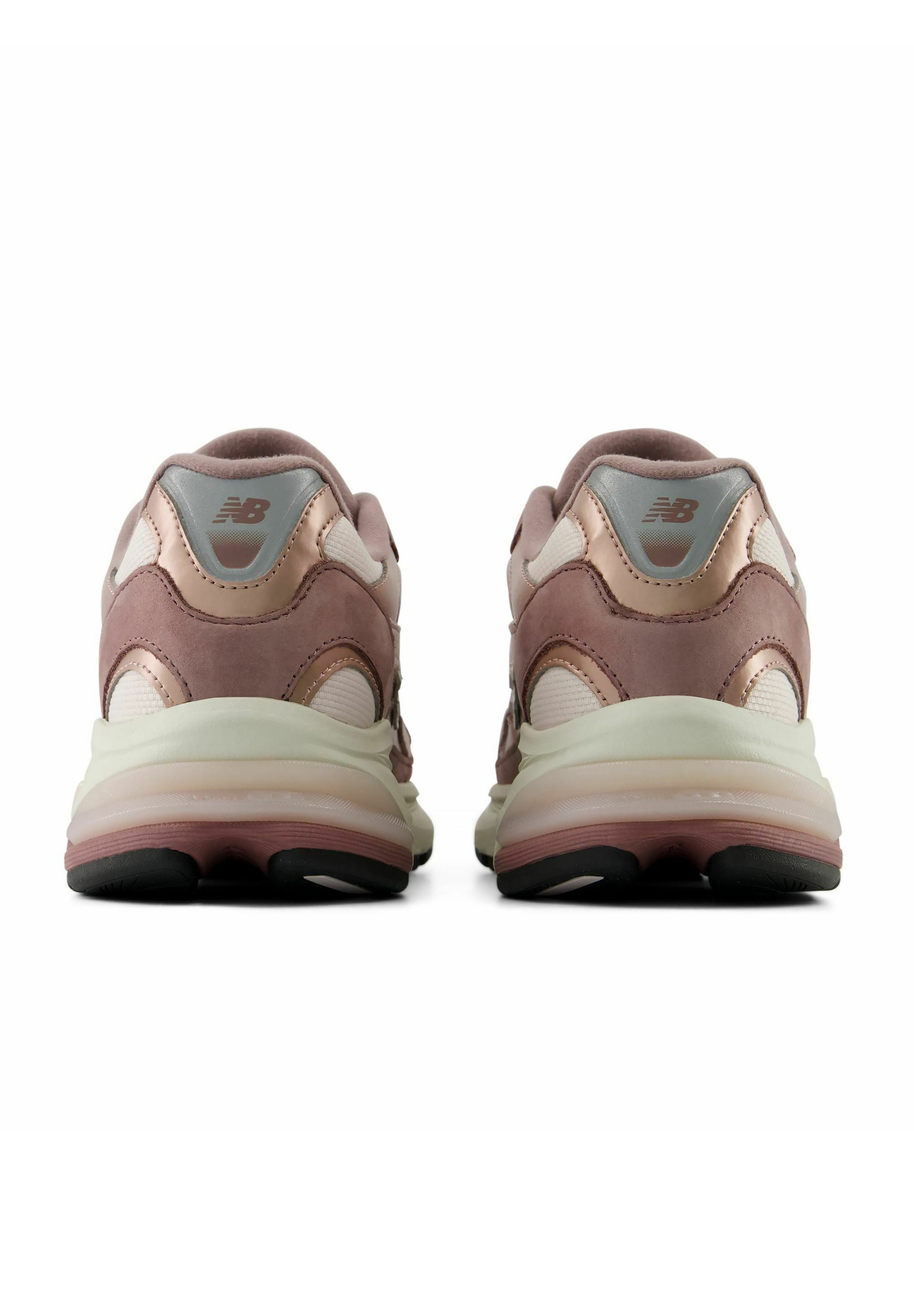Par de zapatillas New Balance rosas y beige mostradas desde atrás con medias suelas blancas gruesas y suelas exteriores negras sobre fondo blanco.
