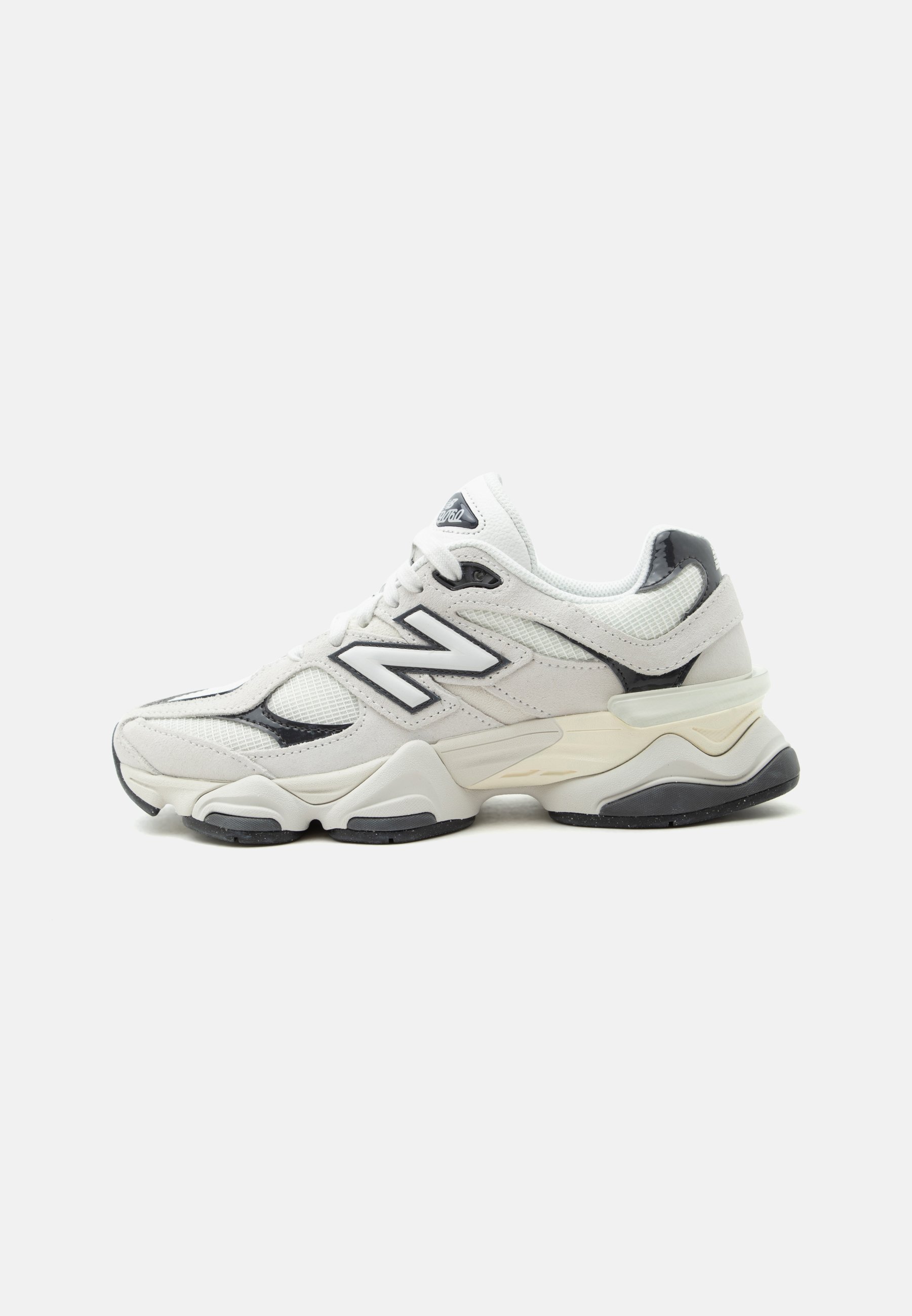 Zapatilla deportiva New Balance blanca y negra con suela gruesa y parte superior de malla y cuero, mostrada de perfil lateral sobre un fondo liso.