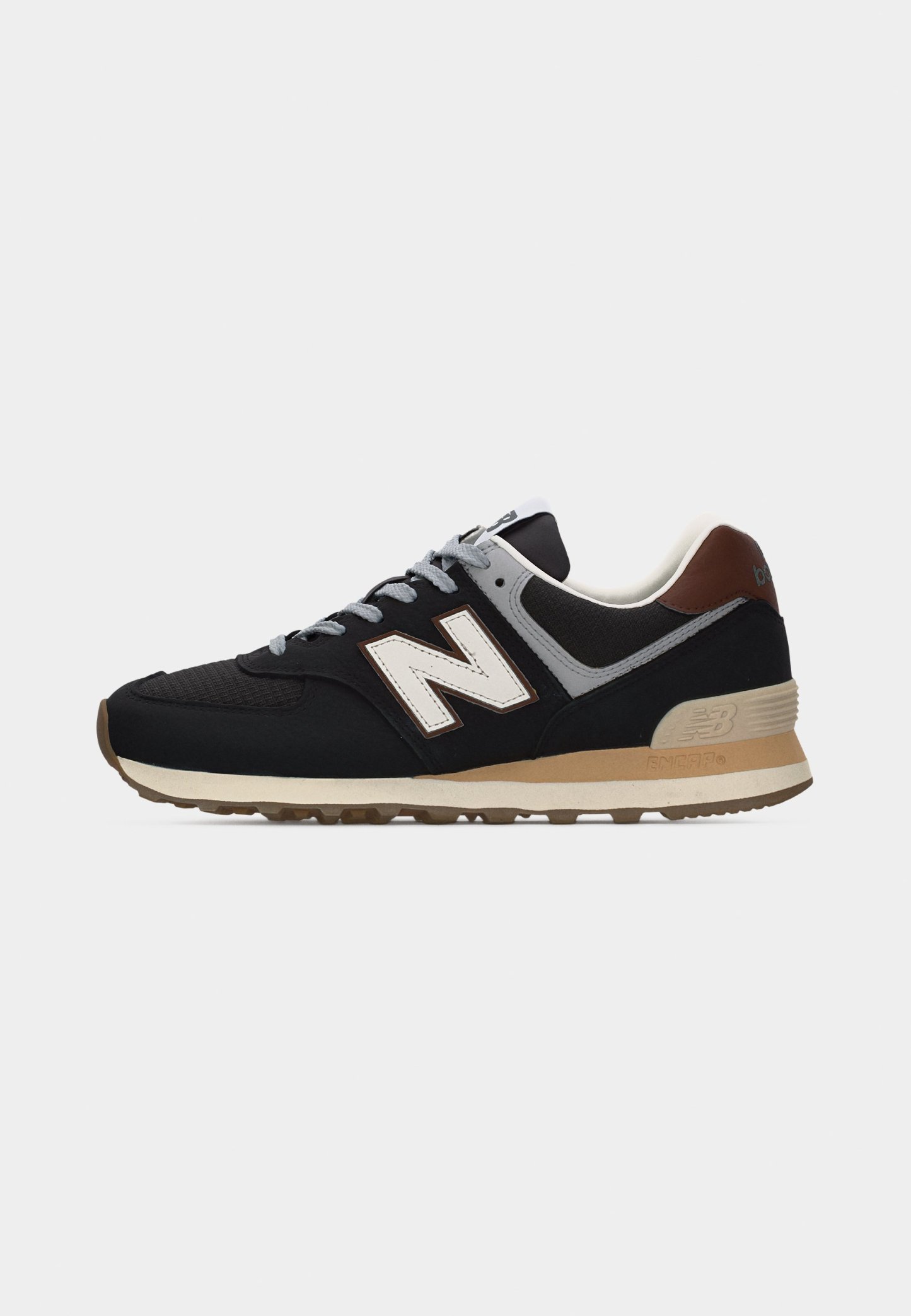 Zapatilla deportiva en negro y beige con cordones grises, detalles en blanco y marrón, y un destacado logo blanco "N" en el lateral.