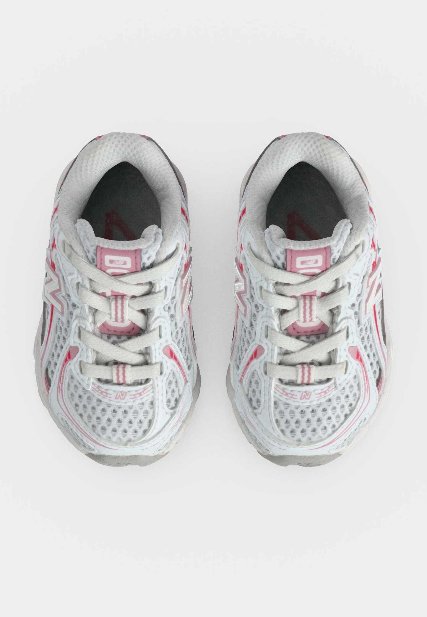 Par de zapatillas deportivas de malla blancas y rosas vistas desde arriba, con cordones atados y logo visible de la marca en los laterales.