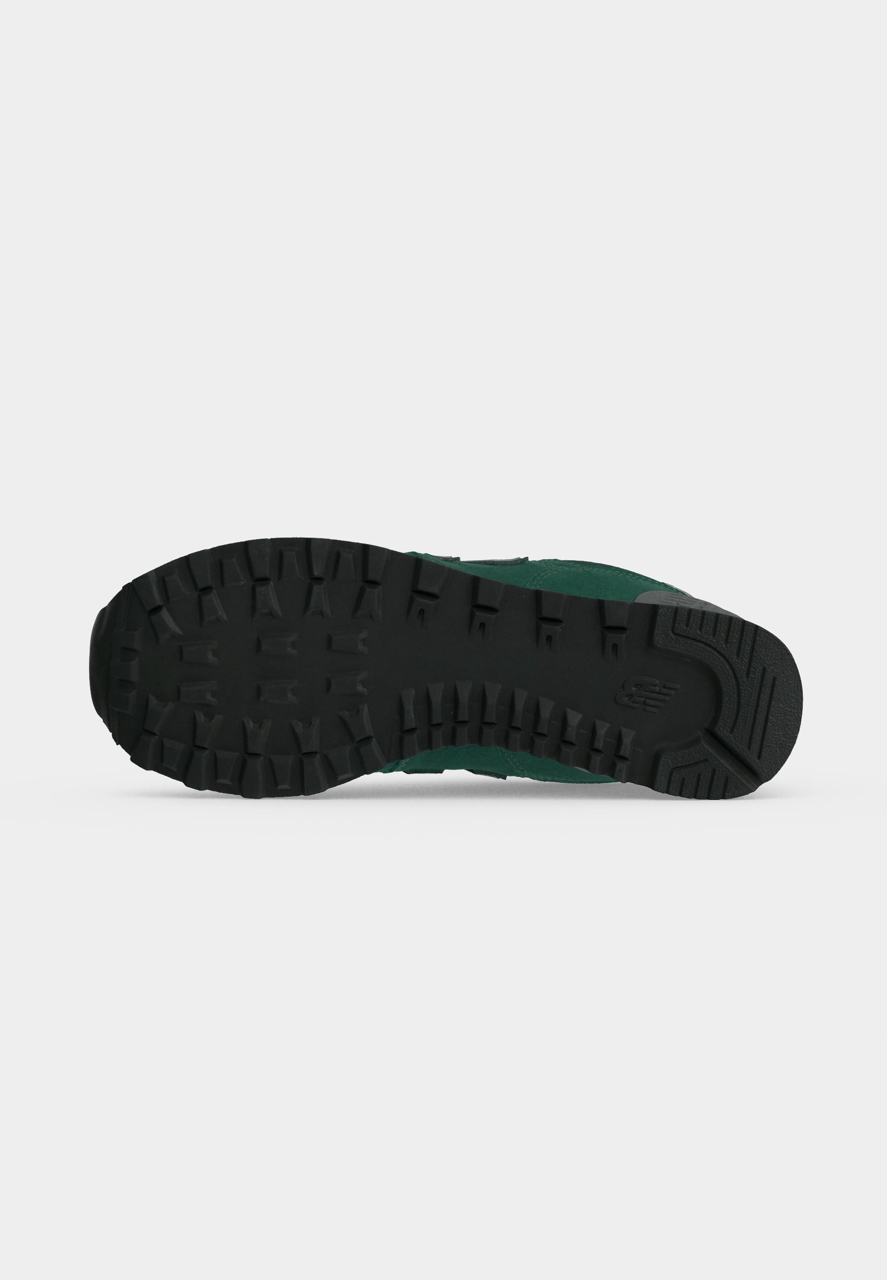 Suela de goma negra de una zapatilla verde que muestra tacos profundos para tracción y el logo de New Balance cerca del talón.