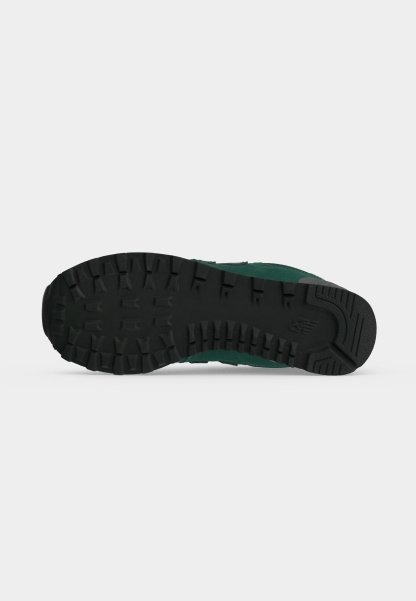 Suela de goma negra de una zapatilla verde que muestra tacos profundos para tracción y el logo de New Balance cerca del talón.