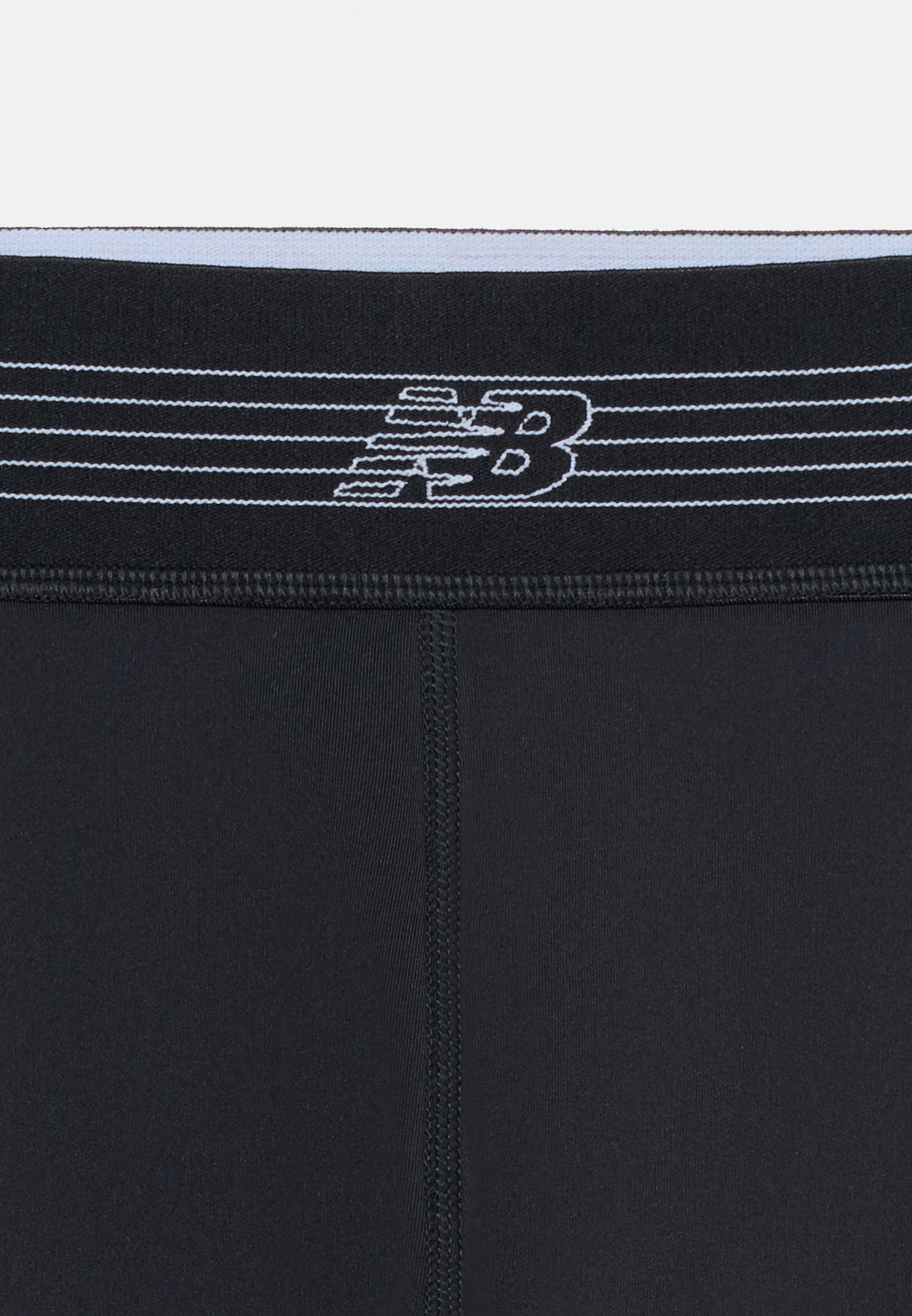 Leggings deportivos negros con costura central cosida y cintura negra con patrón de rayas blancas y logo de New Balance.