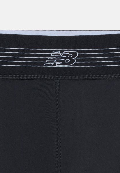 Leggings deportivos negros con costura central cosida y cintura negra con patrón de rayas blancas y logo de New Balance.