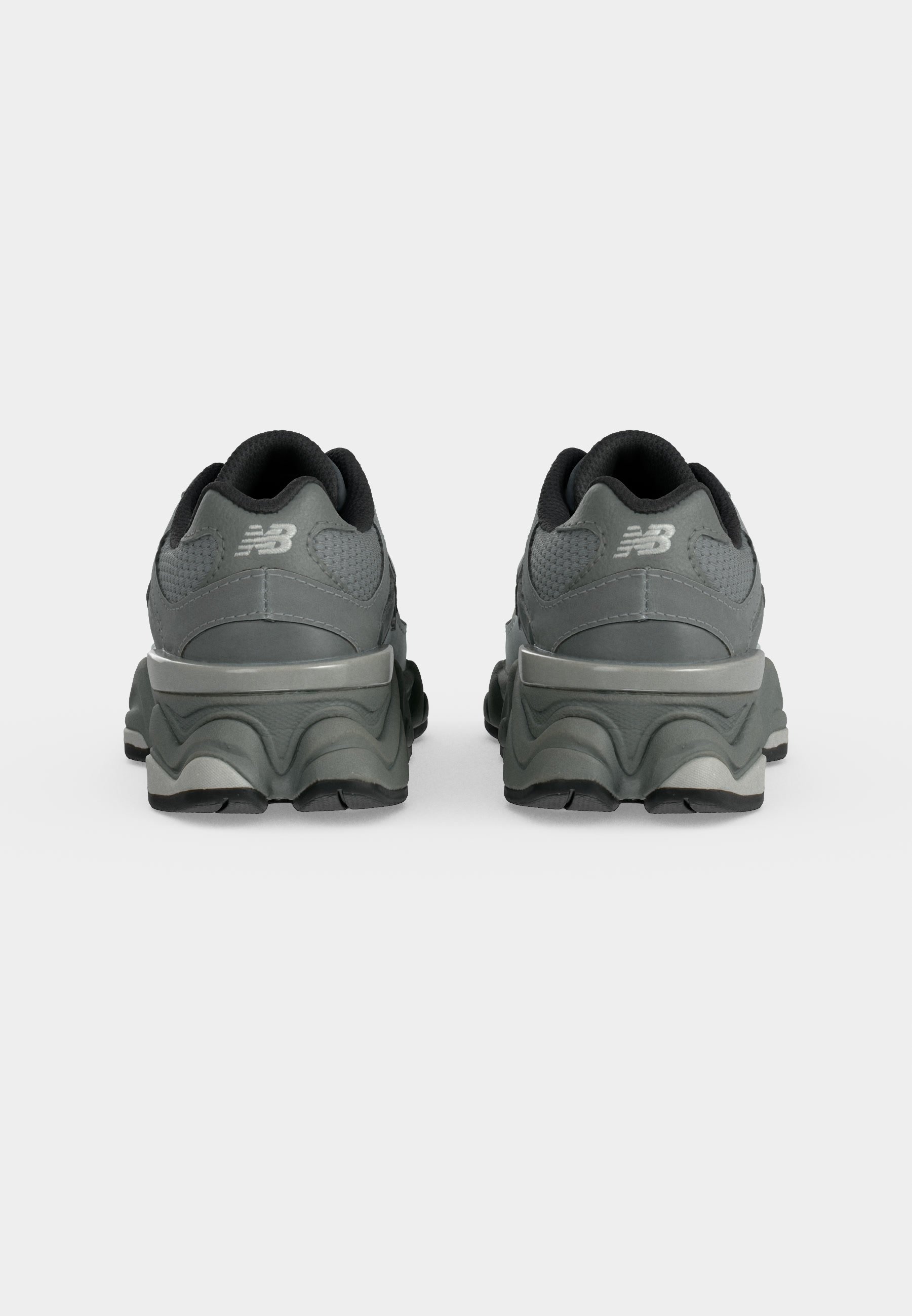 Par de zapatillas New Balance de color gris oscuro vistas desde atrás, con suelas gruesas y cuellos acolchados.