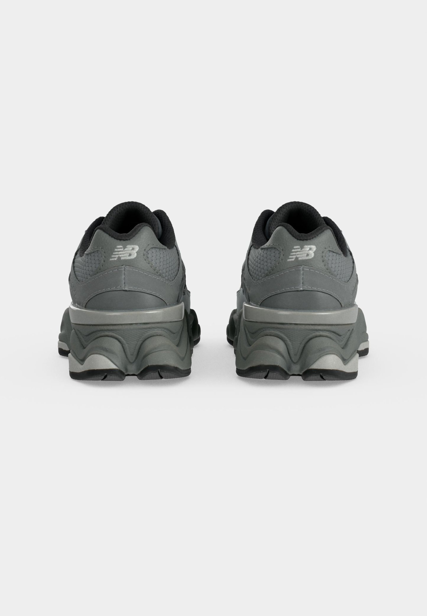 Par de zapatillas New Balance de color gris oscuro vistas desde atrás, con suelas gruesas y cuellos acolchados.