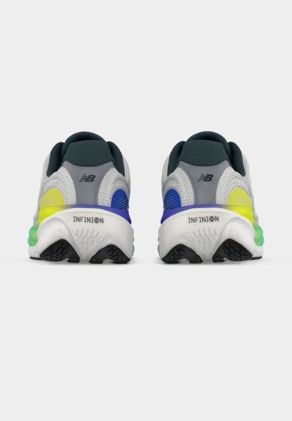 Par de zapatillas para correr New Balance grises y blancas con suelas negras, acentos azul y amarillo, vistas desde atrás sobre un fondo blanco.